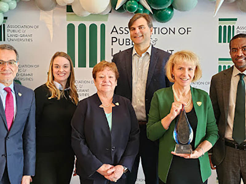 President Kimberly Andrews Espy holds APLU award while standing with other WSU administrators 