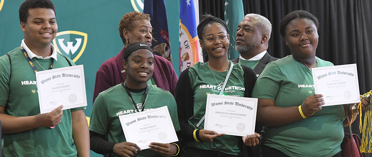 Students smiling and holding up Wayne State University certificates