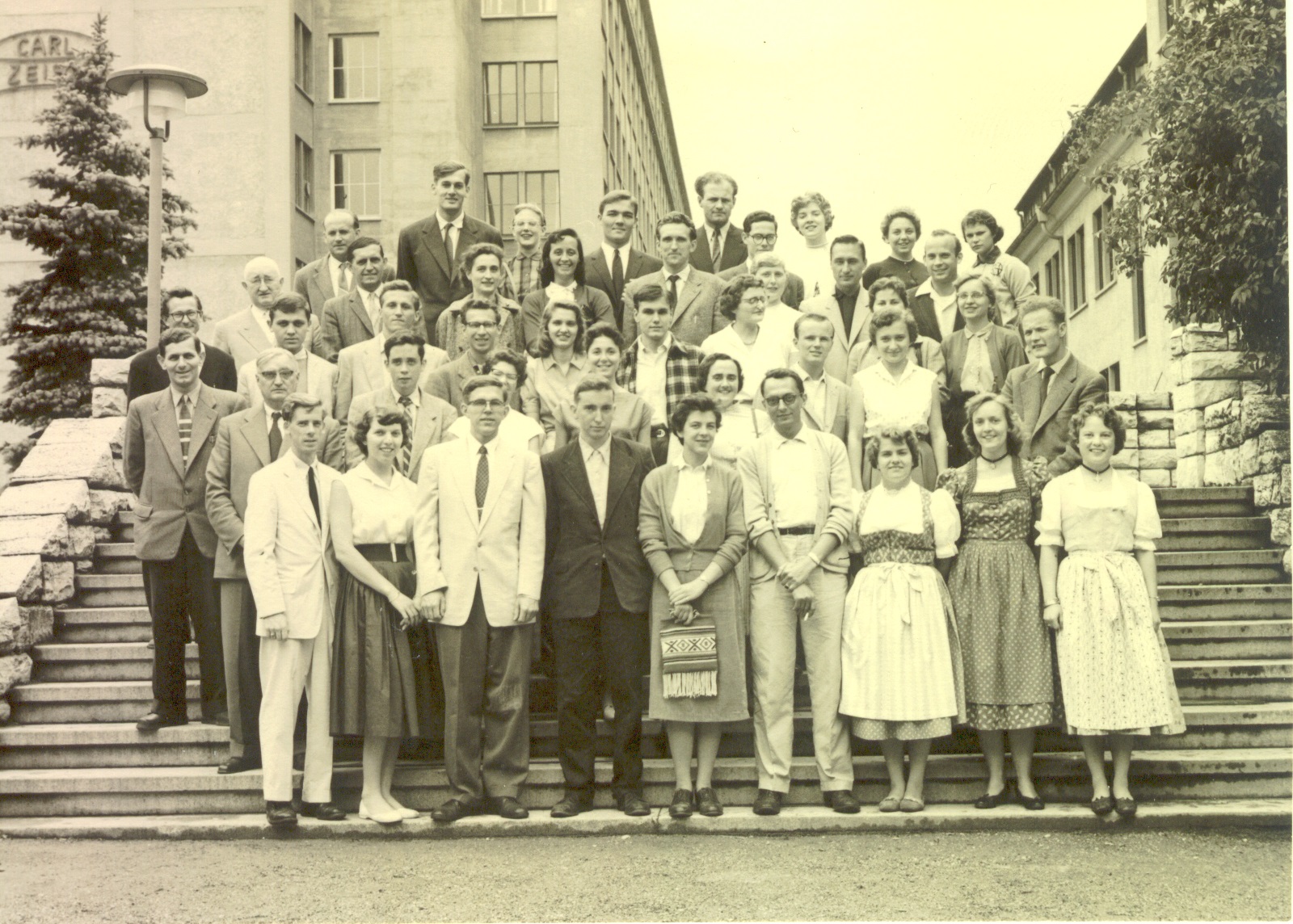 JYM 1956-57 Class photo: Ken Wiggins is in the second row, third from right in the white blazer. In the second row far left: Herr Hildebrand ( JYM office manager) . In the second to back row, the dark-haired man on the far left is JYM resident director, Prof. Dobert; next to him is a young Frau Dr. Riegler and next to her, the JYM staff secretary, Pat Wilson. Just in front of Dr. Dobert is Ken Kurze in a light-colored blazer