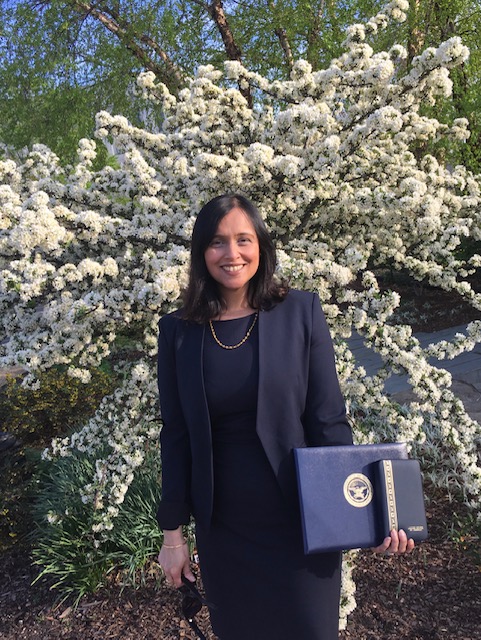 Picture of Maya holding award in front of tree